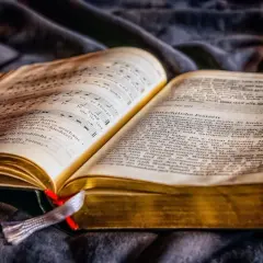 Otwarta księga z nutami i tekstem, symbolizująca motyw dobra i zła w literaturze.