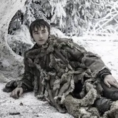 Chłopiec w futrzanym płaszczu leży w śniegu, otoczony mroźnym lasem. Czeka na nadejście **wiatrów zimy**.