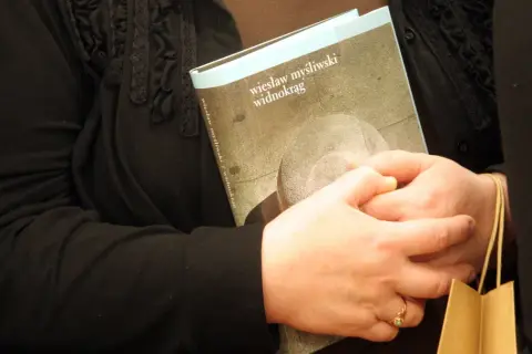 Dwie osoby trzymają książkę "Widnokrąg" Wiesława Myśliwskiego.