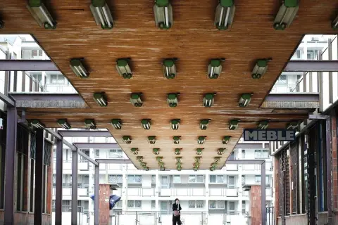 Podświetlany sufit z lampami, przypominający scenografię z filmu o motywie cywilizacji w literaturze. W tle blokowisko i osoba.