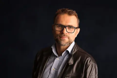 Jacek Bartosiak w skórzanej kurtce i okularach, autor inspirujących książek.