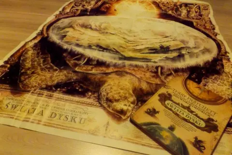 Plakat i książka "Świat Dysku" Terry'ego Pratchetta przedstawiają Wielkiego A'Tuina, kosmicznego żółwia niosącego świat.